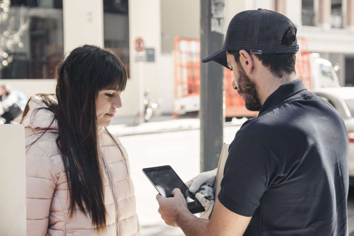 delivery man using digital tablet near female customer (1)