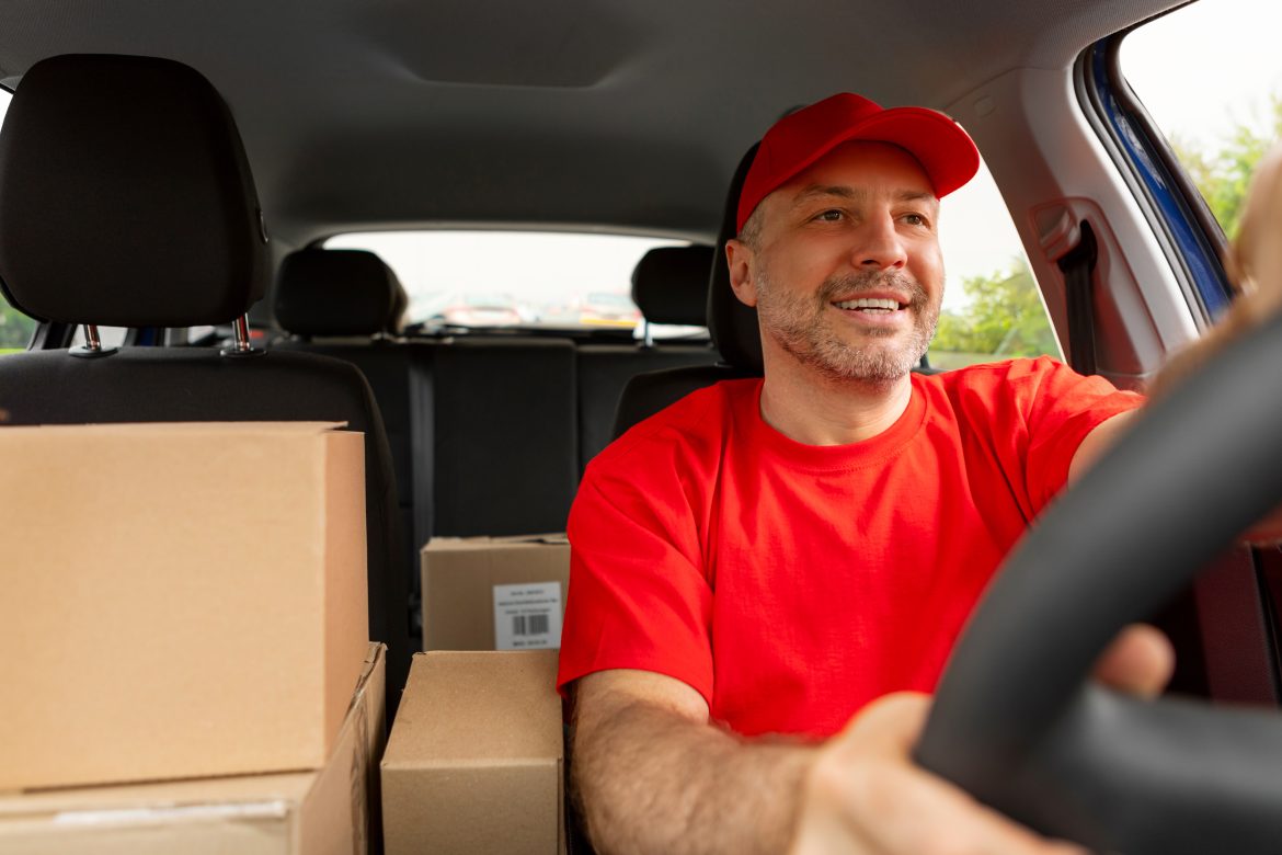 happy middle aged man courier driving car and smiling. delivery and shipping concept